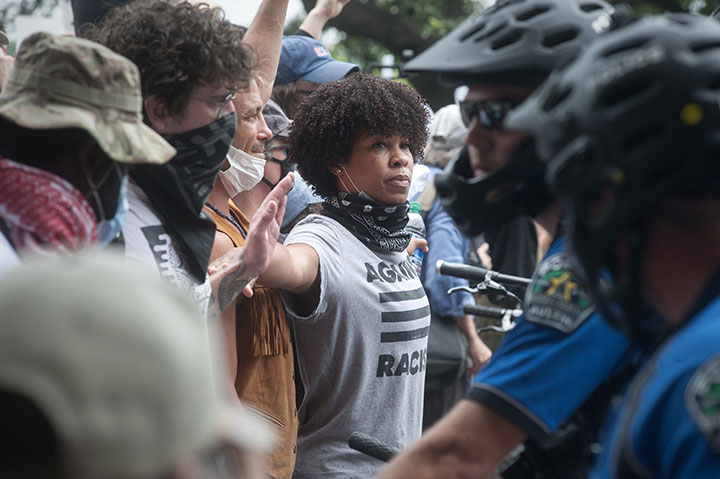 A protester holds back others in front of a police line