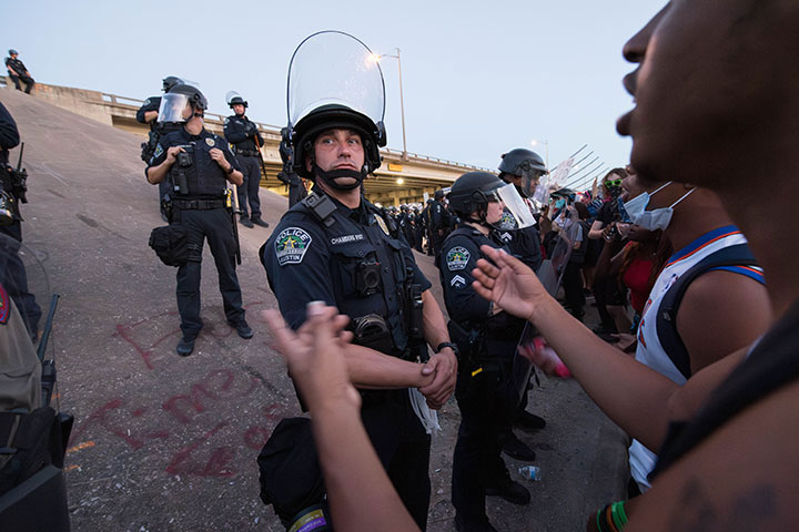 A protester tries to engage a police officer lined-up along Interstate 35