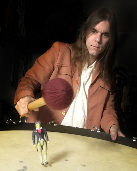 American musician and composer Graham Reynolds bouncing a Beethoven figurine off a kettle drum in his home studio