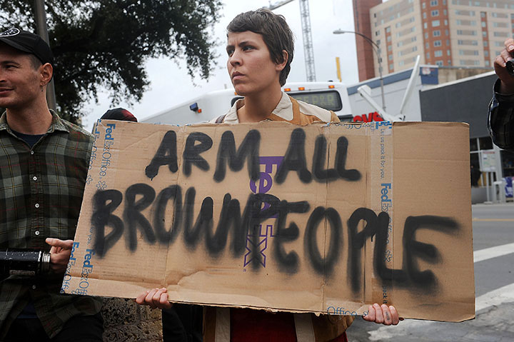 A counter-protester carries a sign that reads 'arm all brown people' during an open carry demonstration