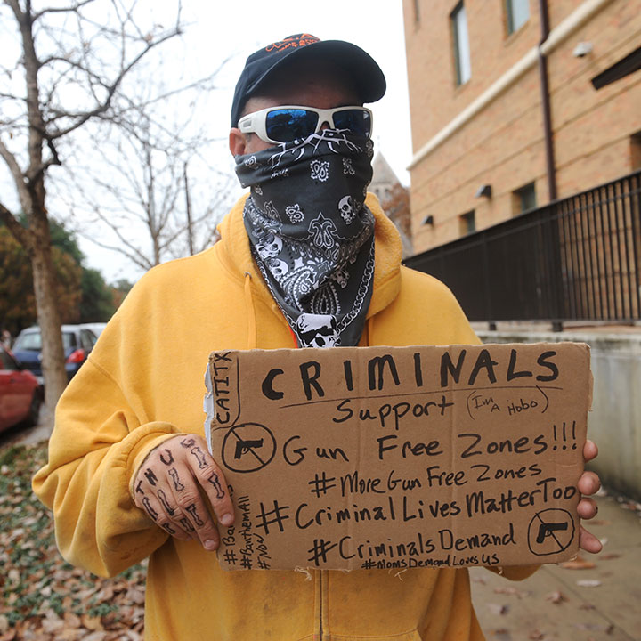A gun rights activist holds a sign suggesting criminals support gun free zones during an open carry demonstration