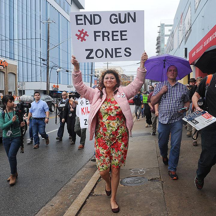 A counter-protester carries a sign that reads 'end all gun free zones' alongside gun rights activists during an open carry demonstration