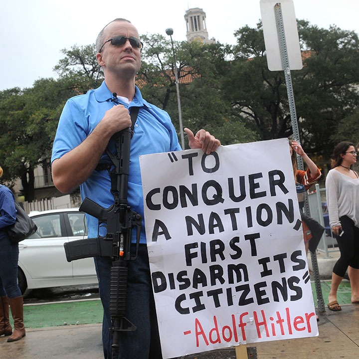 A gun rights activist holds a sign with a quote misattributed to Adolf Hitler during an open carry demonstration near the University of Texas