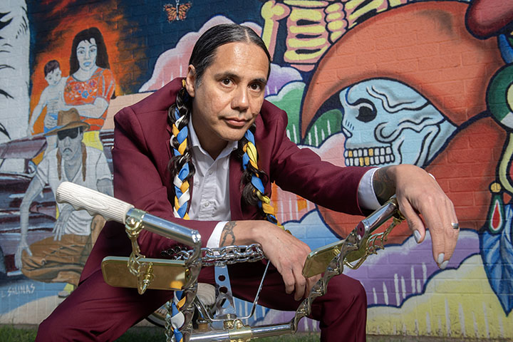 Musician Nelson Valente Aguilar of Como Las Movies poses in front of the Chicano Park Mural